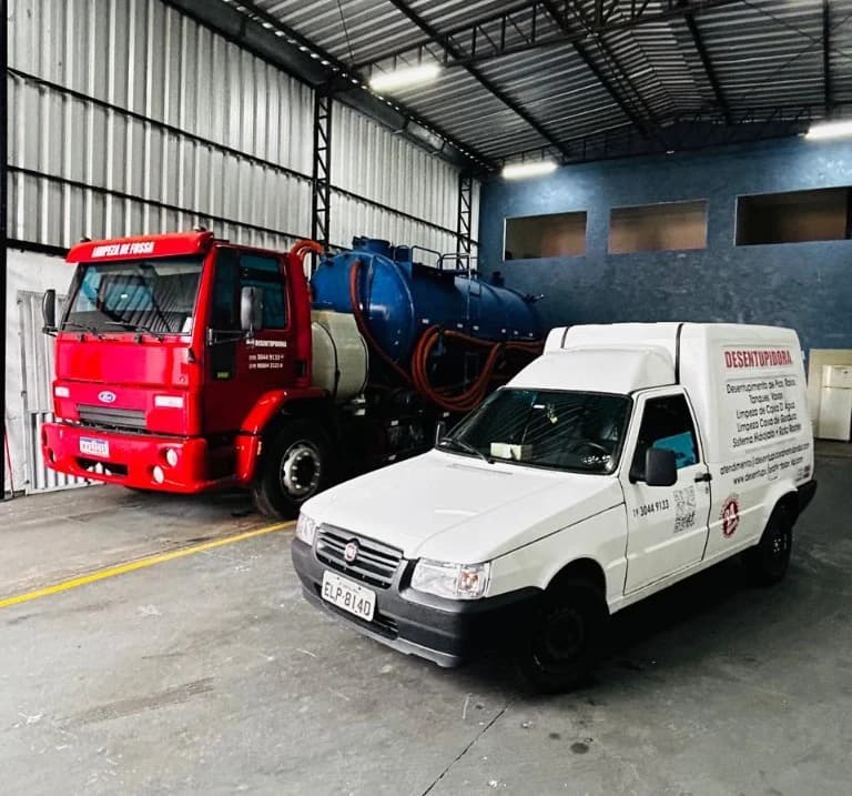 Frota Hortofrança no galpão: caminhão de limpeza de fossa e fiorino de desentupimento